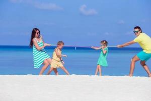 lycklig familj spelar tillsammans på vit strand foto