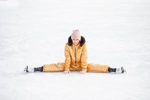 liten förtjusande flicka Sammanträde på is med skridskor efter falla foto