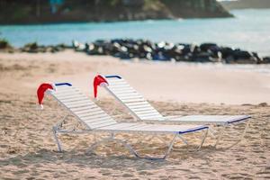 närbild santa hatt på stol på tropisk vit strand foto