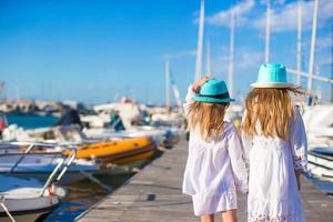 förtjusande liten flickor gående i en hamn under sommar semester foto