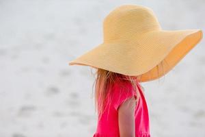 bedårande liten flicka i hatt på stranden under sommarlovet foto