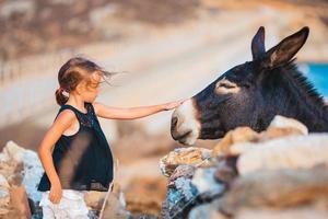 liten flicka med åsna på de ö av mykonos foto