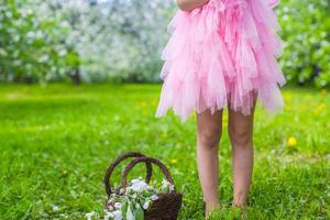 förtjusande liten flicka med sugrör korg i blomstrande äpple trädgård foto