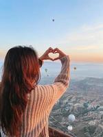 Lycklig kvinna under soluppgång tittar på varm luft ballonger i Kappadokien, Kalkon foto