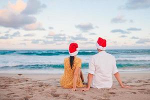 Lycklig par i santa hattar på jul strand semester foto