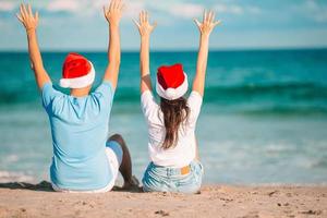 jul Lycklig par i santa hattar på strand semester foto
