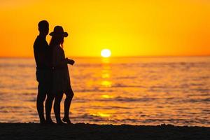 romantiskt par på stranden vid färgglad solnedgång på bakgrunden foto