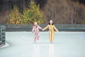 förtjusande flickor skridskoåkning på is rink utomhus i vinter- snö dag foto