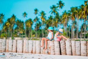 liten Lycklig rolig flickor ha en massa av roligt på tropisk strand spelar tillsammans. foto