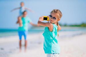 liten flicka gör foto på telefonen av familjen på stranden