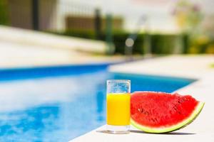 sommar och färsk tema röd mogen skiva vattenmelon och glas av orange juice nära slå samman foto