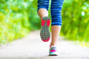 närbild på sko av idrottare löpare kvinna fötter löpning på väg foto