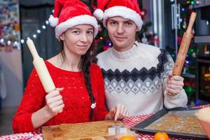 Lycklig familj i santa hattar bakning jul pepparkaka småkakor tillsammans foto