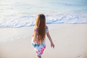 förtjusande liten flicka gående på vit tropisk strand foto