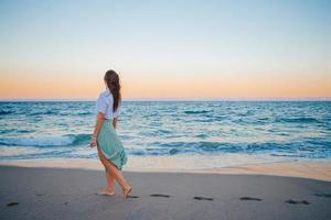 Lycklig kvinna njuter skön solnedgång på de strand foto