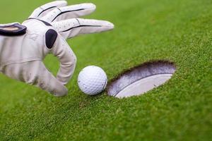 golfspelare man skjuter golfboll i hålet foto