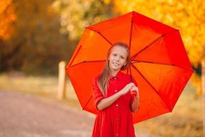 Lycklig barn flicka skrattar under röd paraply foto