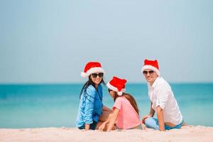 Lycklig familj i santa hatt på sommar semester foto