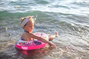 liten flicka har roligt på tropisk strand med turkos hav vatten foto