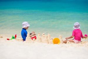 två barn framställning sand slott och spelar på tropisk strand foto