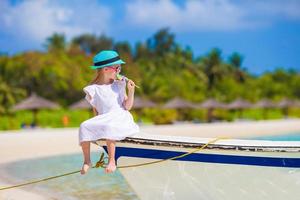 förtjusande Lycklig leende liten flicka i hatt på strand semester foto