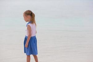 bedårande glad liten flicka ha kul på grunt vatten på strandsemester foto