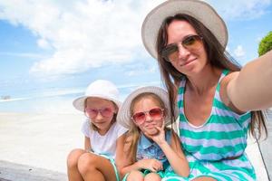Lycklig familj tar selfie på tropisk strand foto