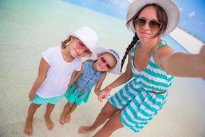 mor och liten flickor tar selfie på tropisk strand foto