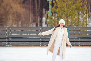 leende ung flicka skridskoåkning på is rink utomhus foto