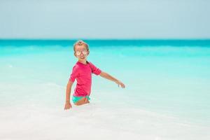 förtjusande liten flicka på strand har en massa av roligt i vatten foto