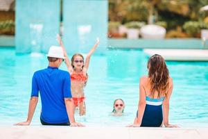 Lycklig familj av fyra i utomhus simning slå samman foto