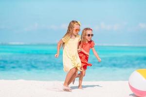 liten förtjusande flickor spelar med luft boll på de strand. barn har roligt på de havsstrand foto