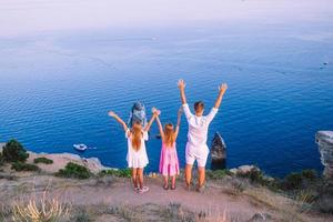 Lycklig familj av fyra gående i de bergen på de solnedgång foto