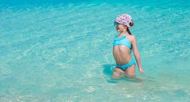 förtjusande liten flicka i de hav på tropisk strand semester foto