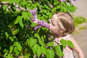 liten förtjusande flicka nära blommor i de trädgård foto