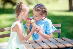 liten flickor äter glass utomhus på sommar i utomhus- Kafé foto