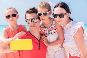 ung skön familj tar selfie på de strand foto