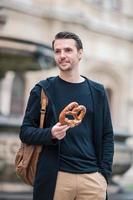 skön ung man innehav pretzel och avkopplande i parkera foto