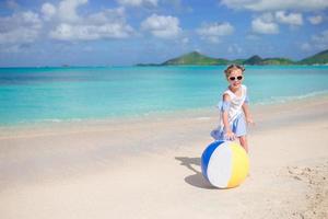 liten bedårande flicka som leker på stranden med boll foto