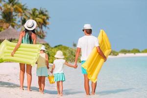 lycklig familj på fyra på vit strand foto