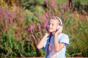 liten förtjusande flicka lyssnande musik i de parkera foto