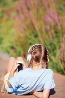 liten förtjusande flicka lyssnande musik i de parkera foto