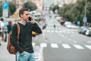 ung caucasian man leende Lycklig använder sig av smartphone utomhus foto