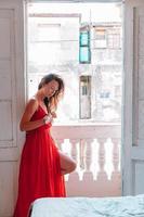 ung attraktiv kvinna i röd klänning på gammal balkong i lägenhet i havana foto