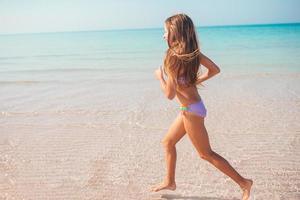 bedårande aktiv liten flicka på stranden under sommarlovet foto