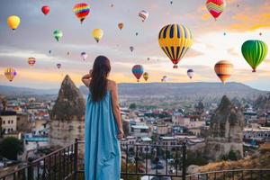 Lycklig ung kvinna under soluppgång tittar på varm luft ballonger i Kappadokien, Kalkon foto