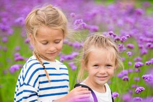 liten förtjusande flickor gående utomhus i blommor fält foto