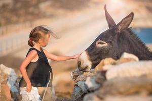 liten flicka med åsna på de ö av mykonos foto