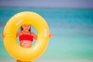 förtjusande flicka med uppblåsbar sudd cirkel på vit strand foto