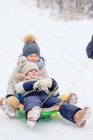 förtjusande liten Lycklig flickor sledding i vinter- snöig dag. foto